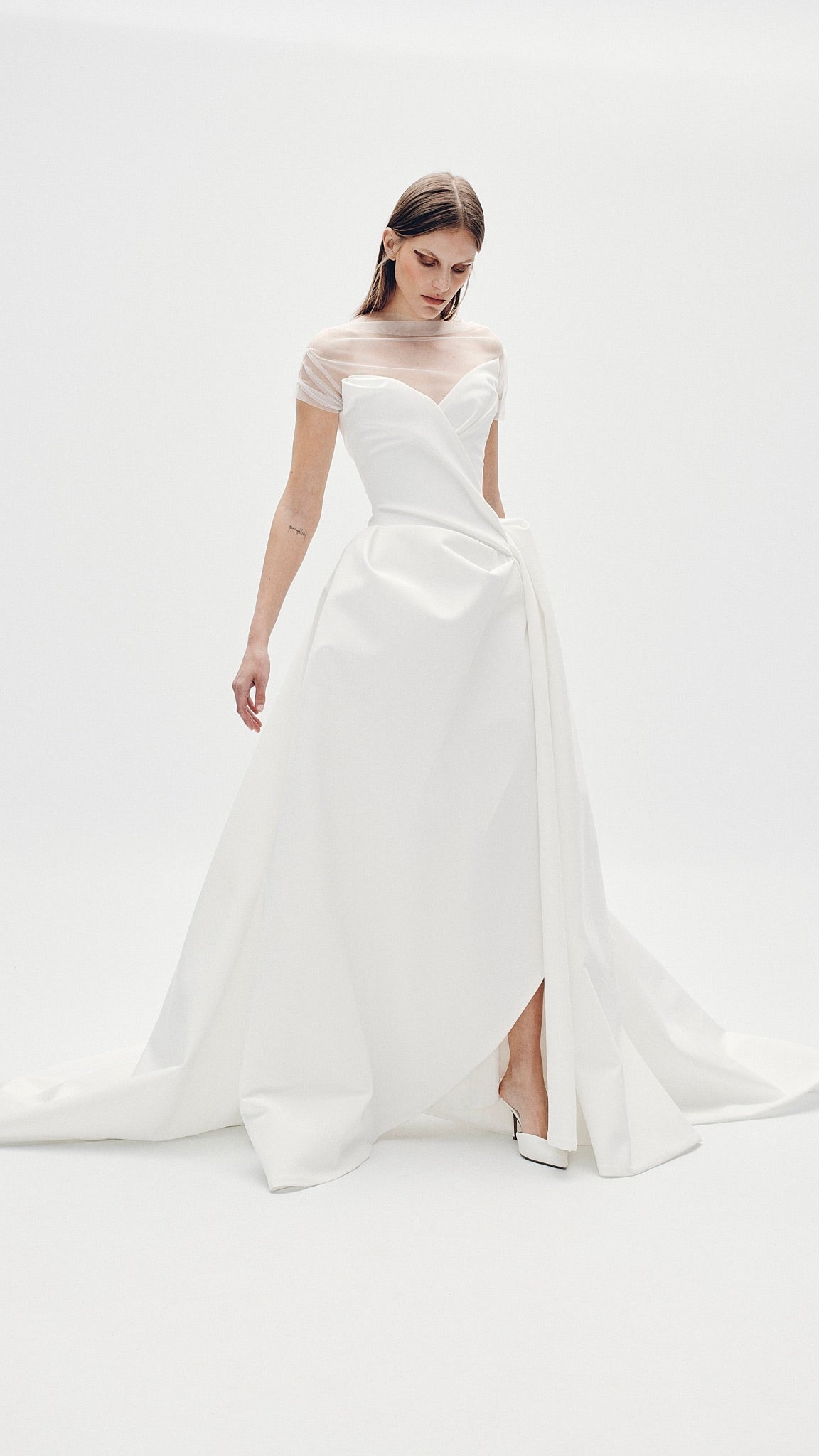 Model wearing the Aliet strapless A-line ballgown with asymmetrical draping and train in a minimalist white studio setting