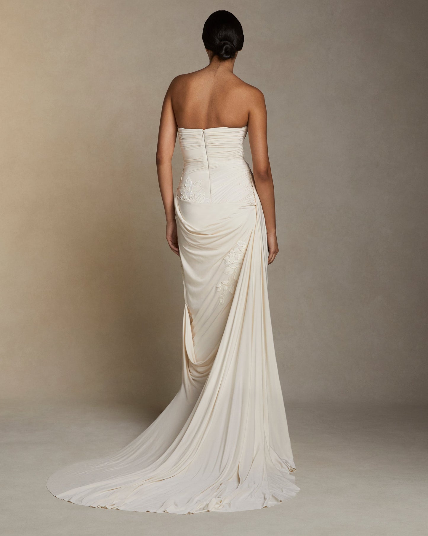 Model wearing the strapless Harris gown with asymmetric cascading drape and long puddle train in a neutral studio setting