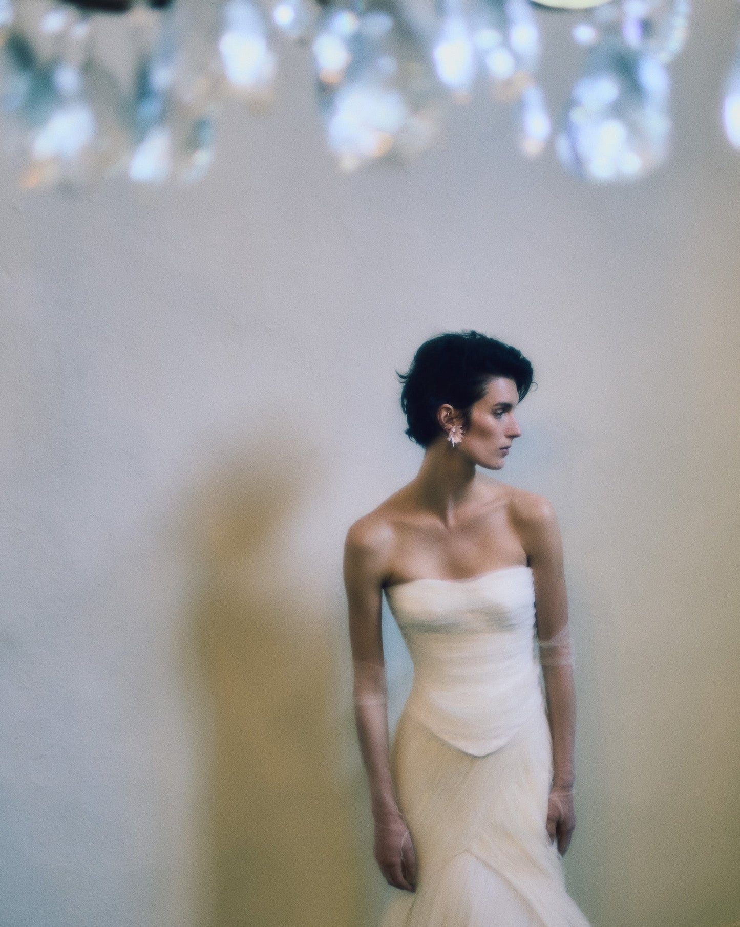 Model wearing the Milo strapless structured corset dress with dipped waist and soft tulle draping in a soft-focus setting