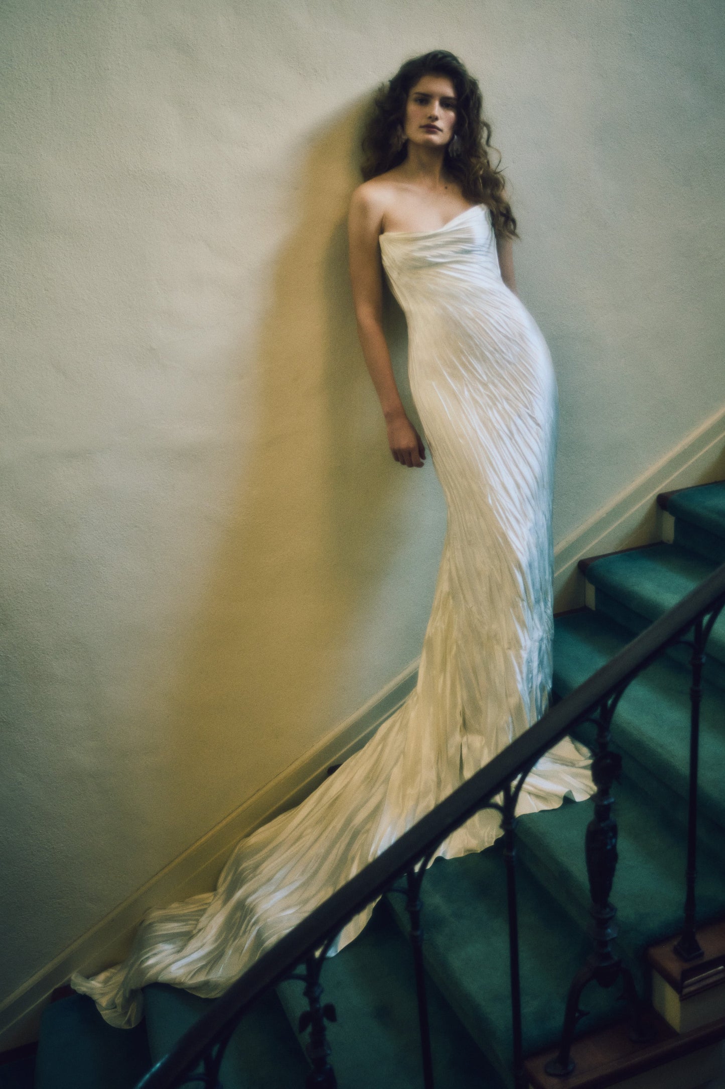 Woman in a white strapless gown standing on a staircase