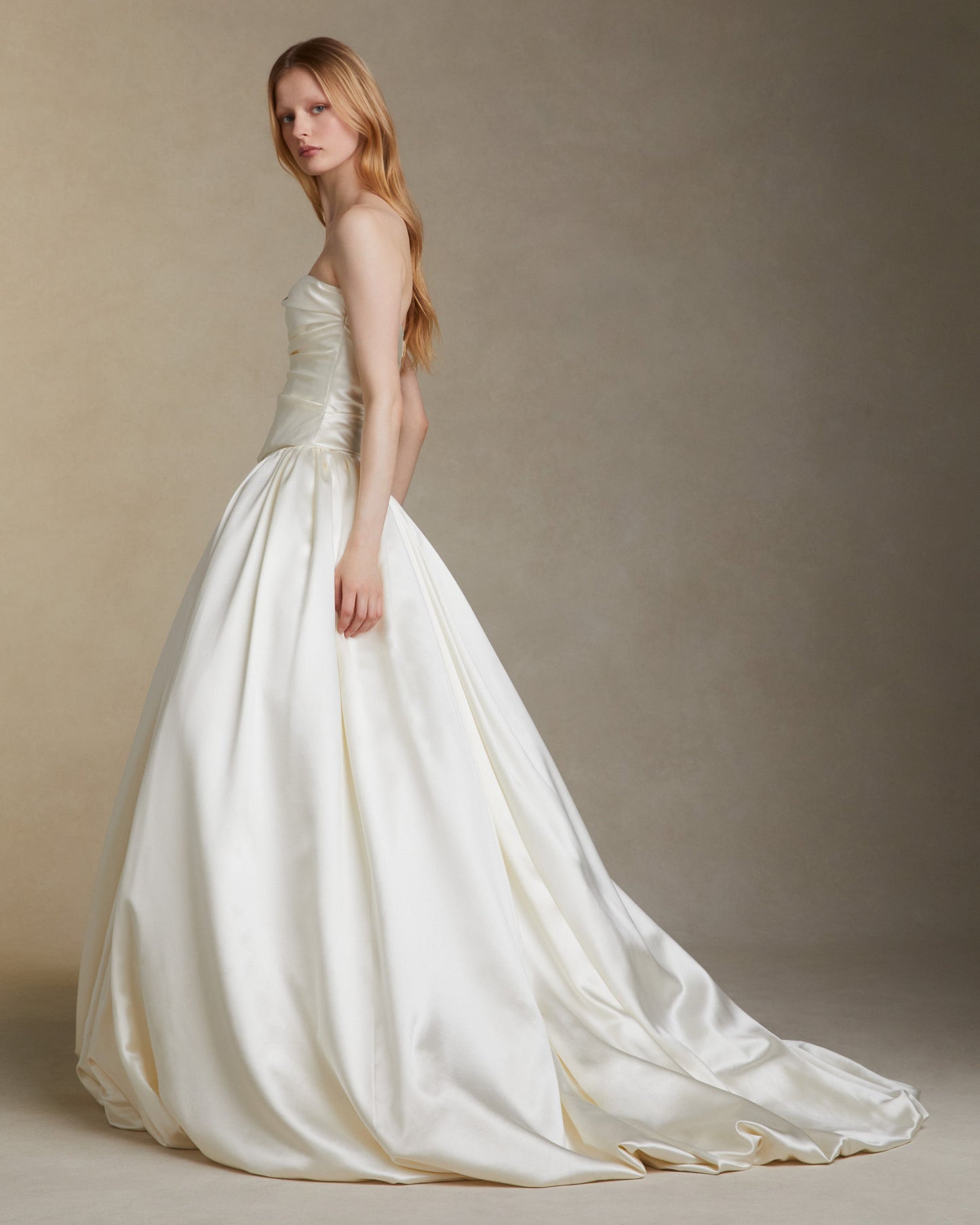 Woman wearing a white wedding dress against a plain background