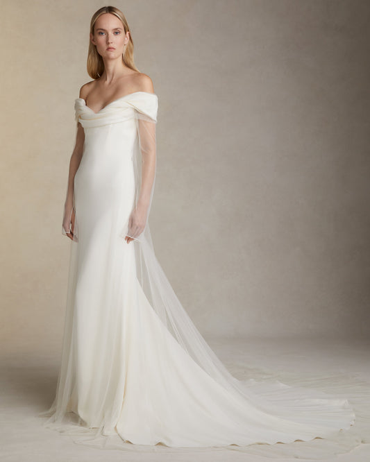 Model wearing the Eloise off-shoulder stretch cady gown with draped bodice and soft tulle overlay in studio setting