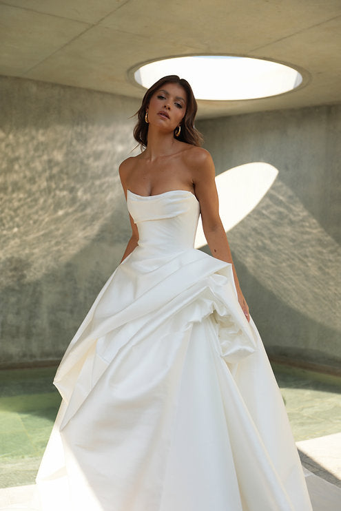 Woman in a white wedding dress standing in a modern architectural setting.