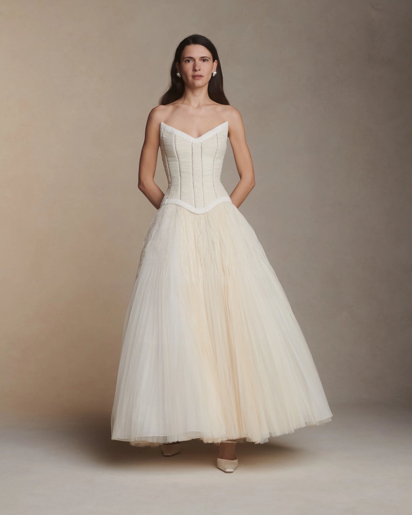 Woman wearing a white strapless gown against a plain background