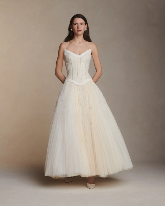 Woman wearing a white strapless gown against a plain background