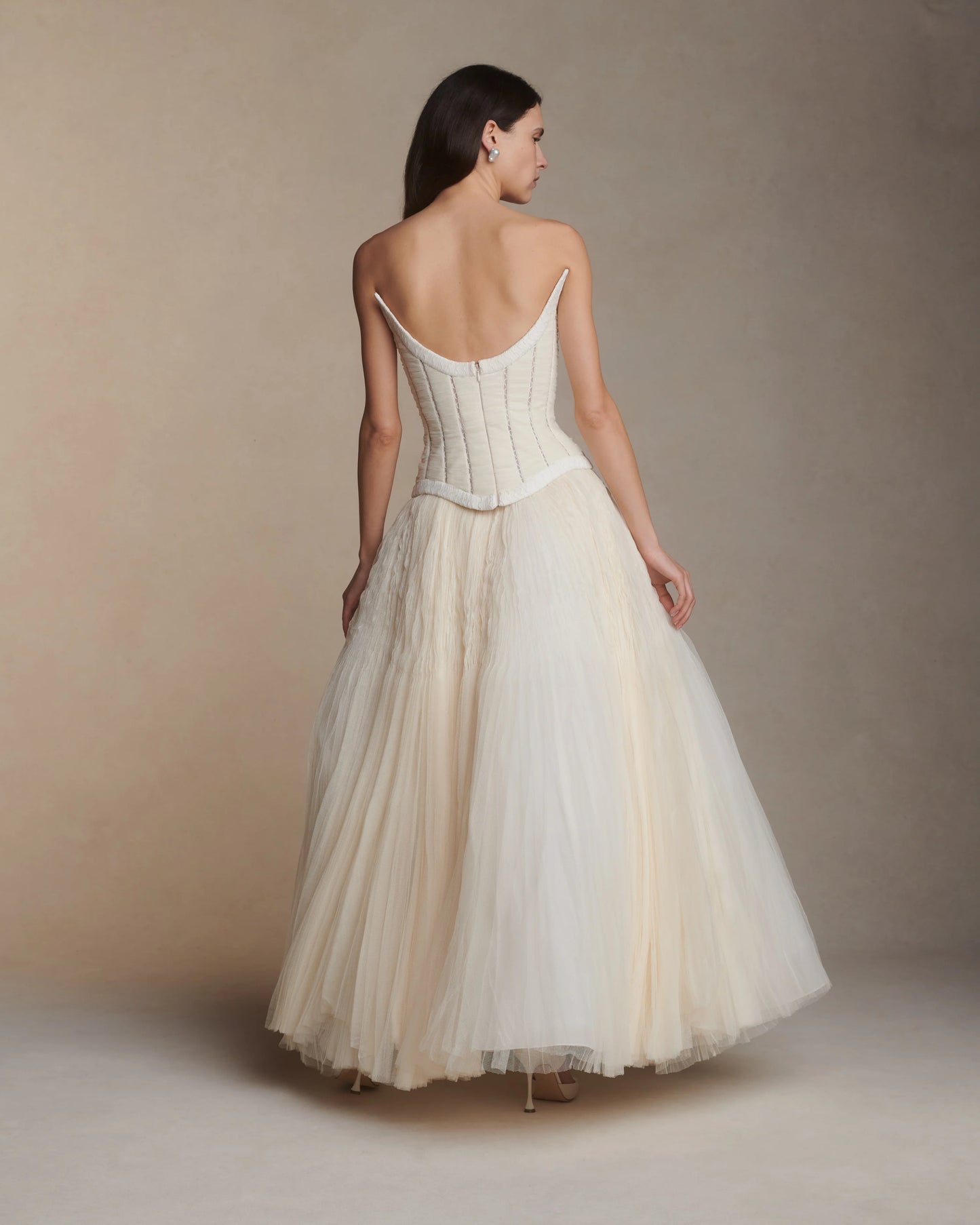 Woman wearing a white dress with thin straps against a beige background