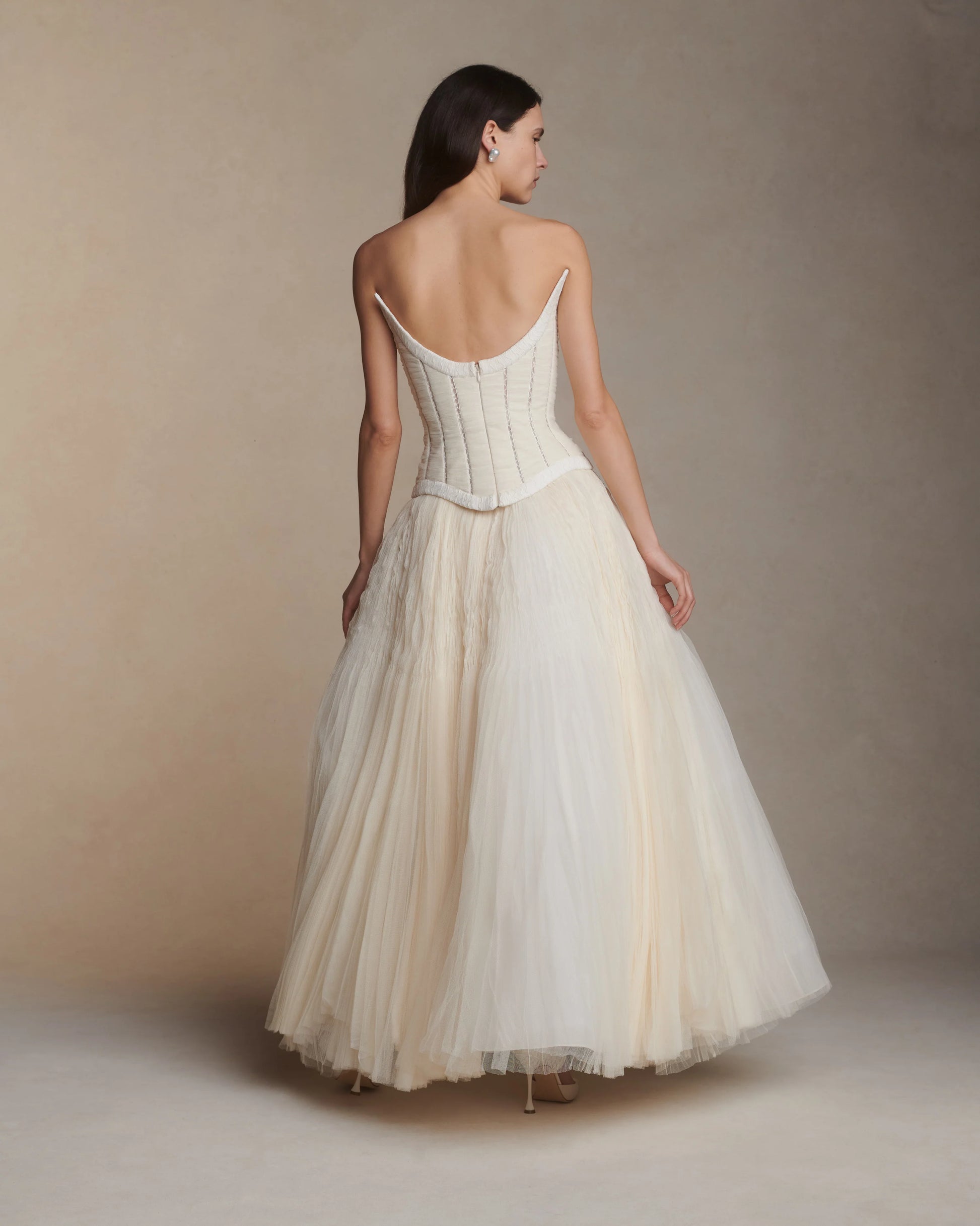 Woman wearing a white dress with thin straps against a beige background