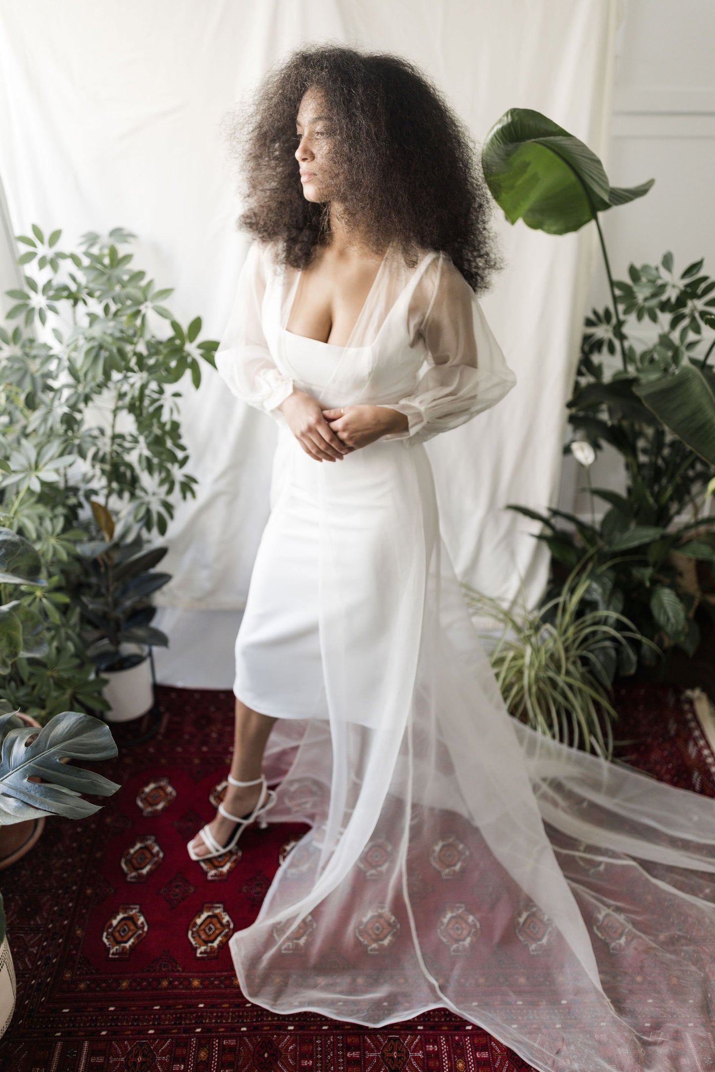 Woman in a white dress standing in a room with plants