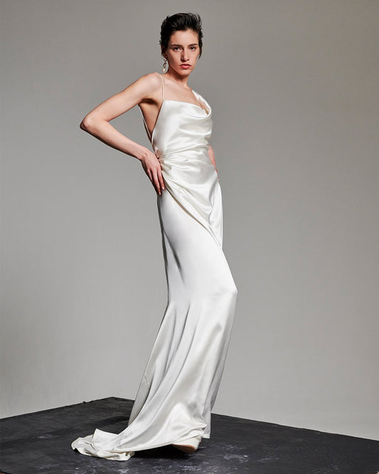 Model wearing the Minerva white satin gown with twisted asymmetric neckline and backless floor-length silhouette
