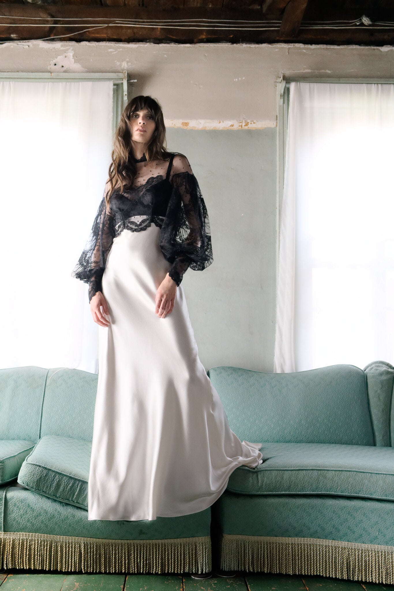 Model wearing the Izzie Topper Victorian-inspired black scallop lace balloon sleeve over-top in a rustic room setting