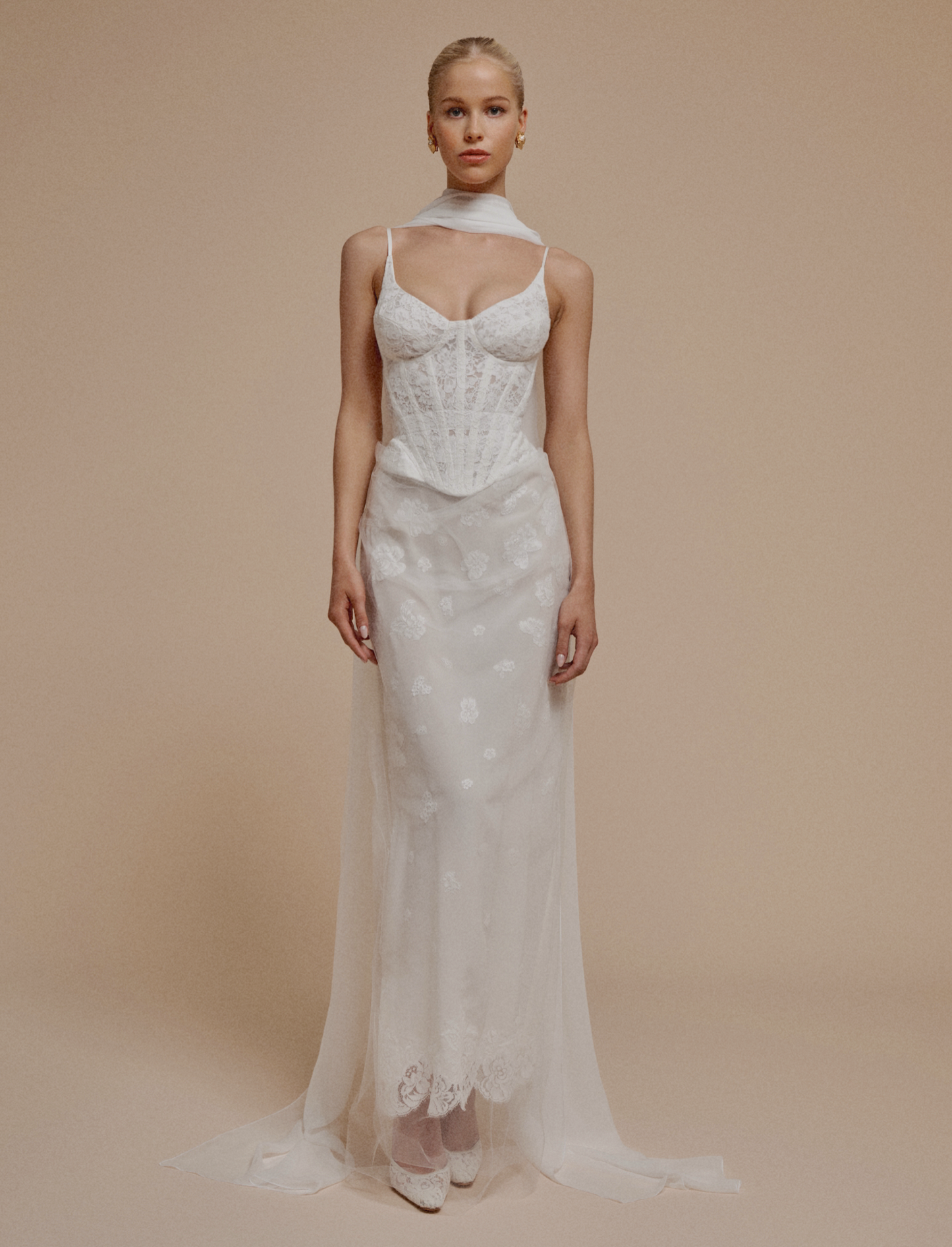 Woman wearing a white lace wedding dress against a beige background