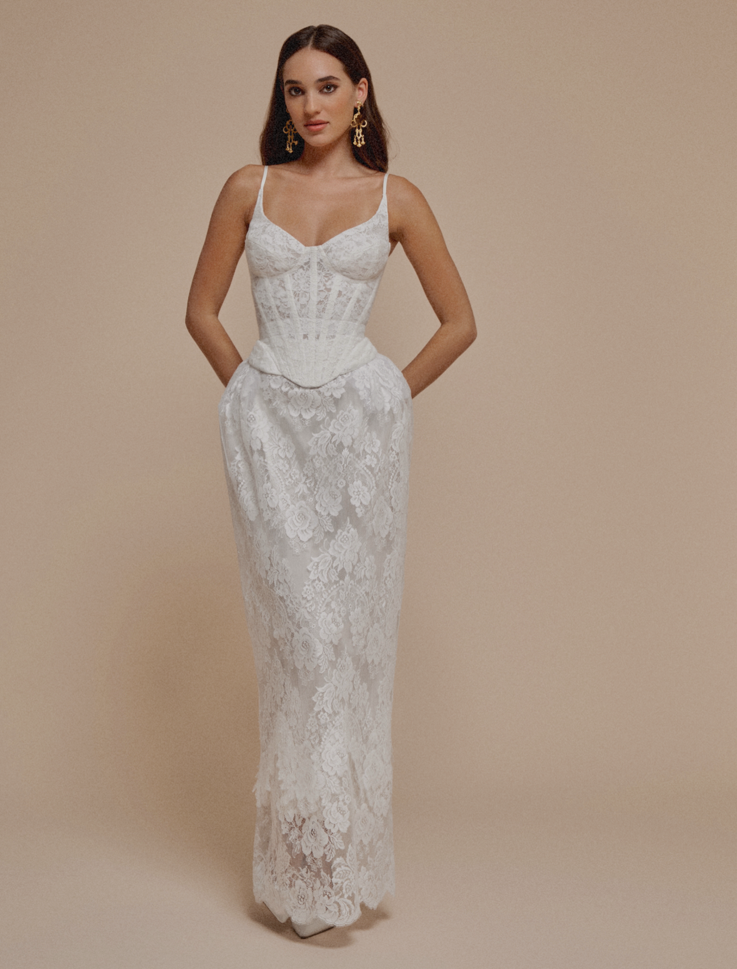 Woman wearing a white lace dress against a beige background