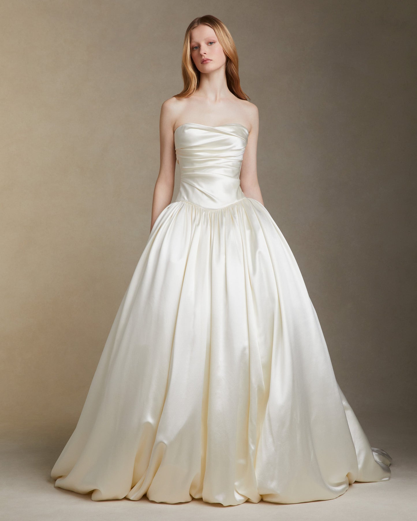 Woman wearing a strapless white wedding dress against a neutral background