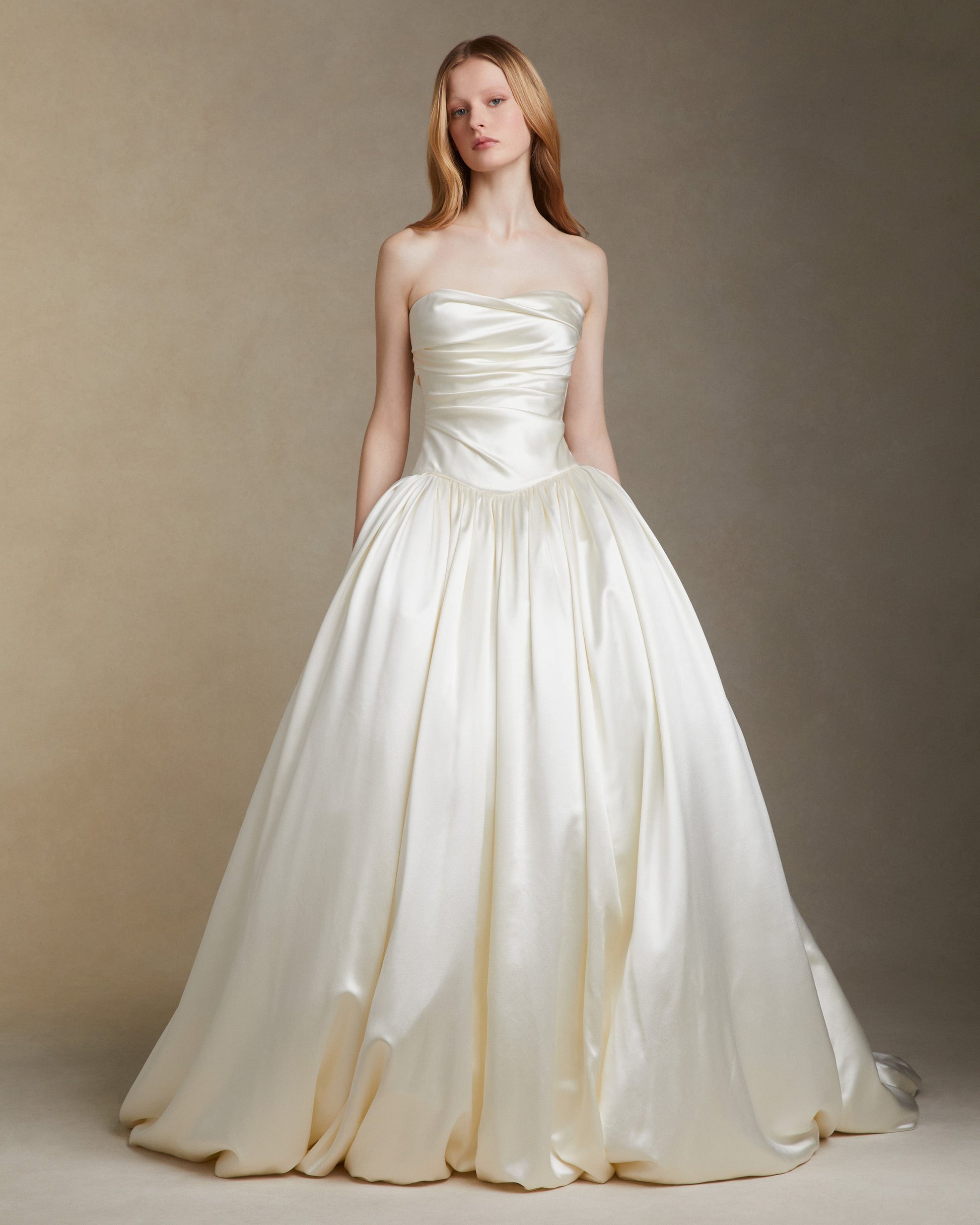 Woman wearing a strapless white wedding dress against a neutral background
