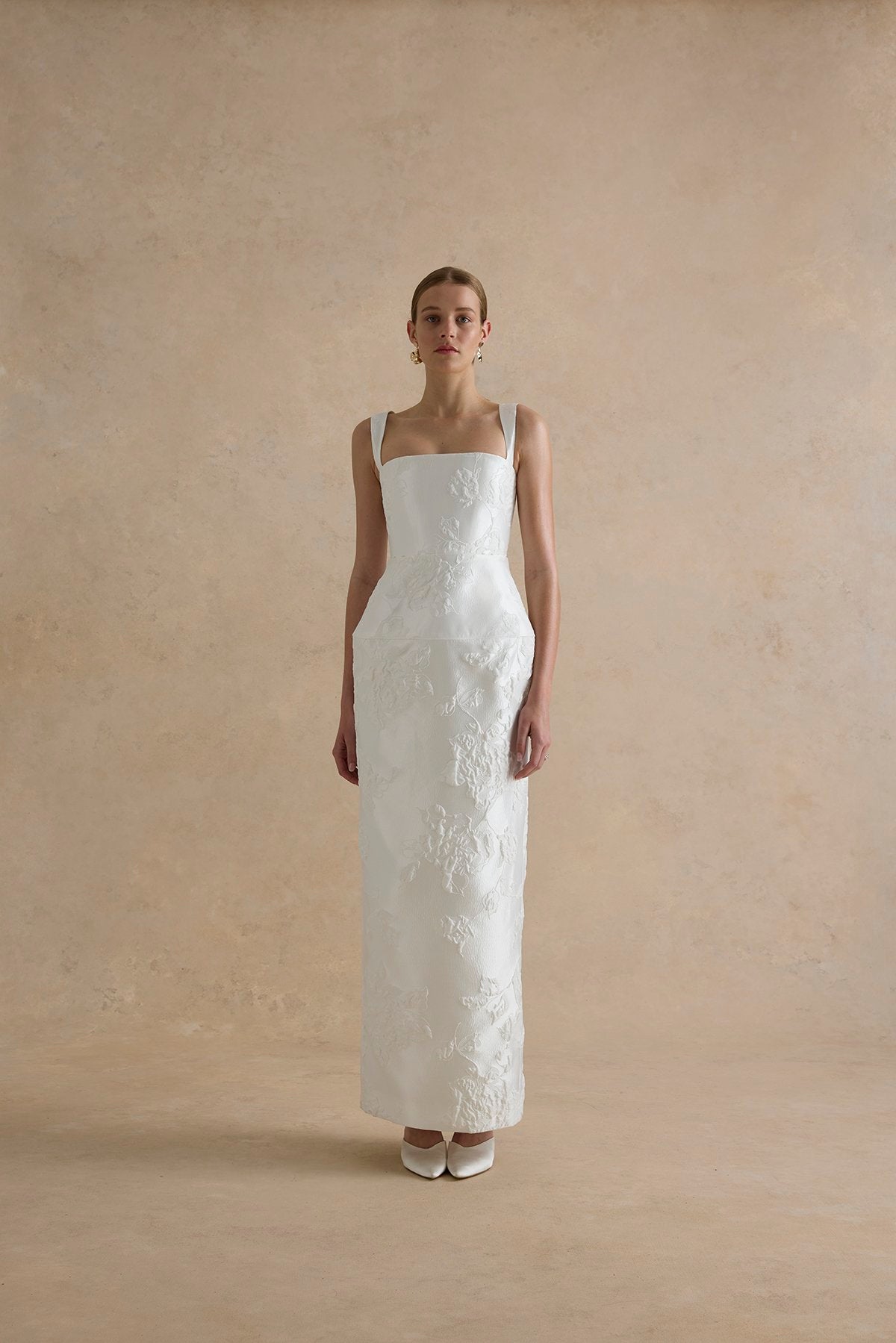 Woman wearing a white wedding dress against a beige background