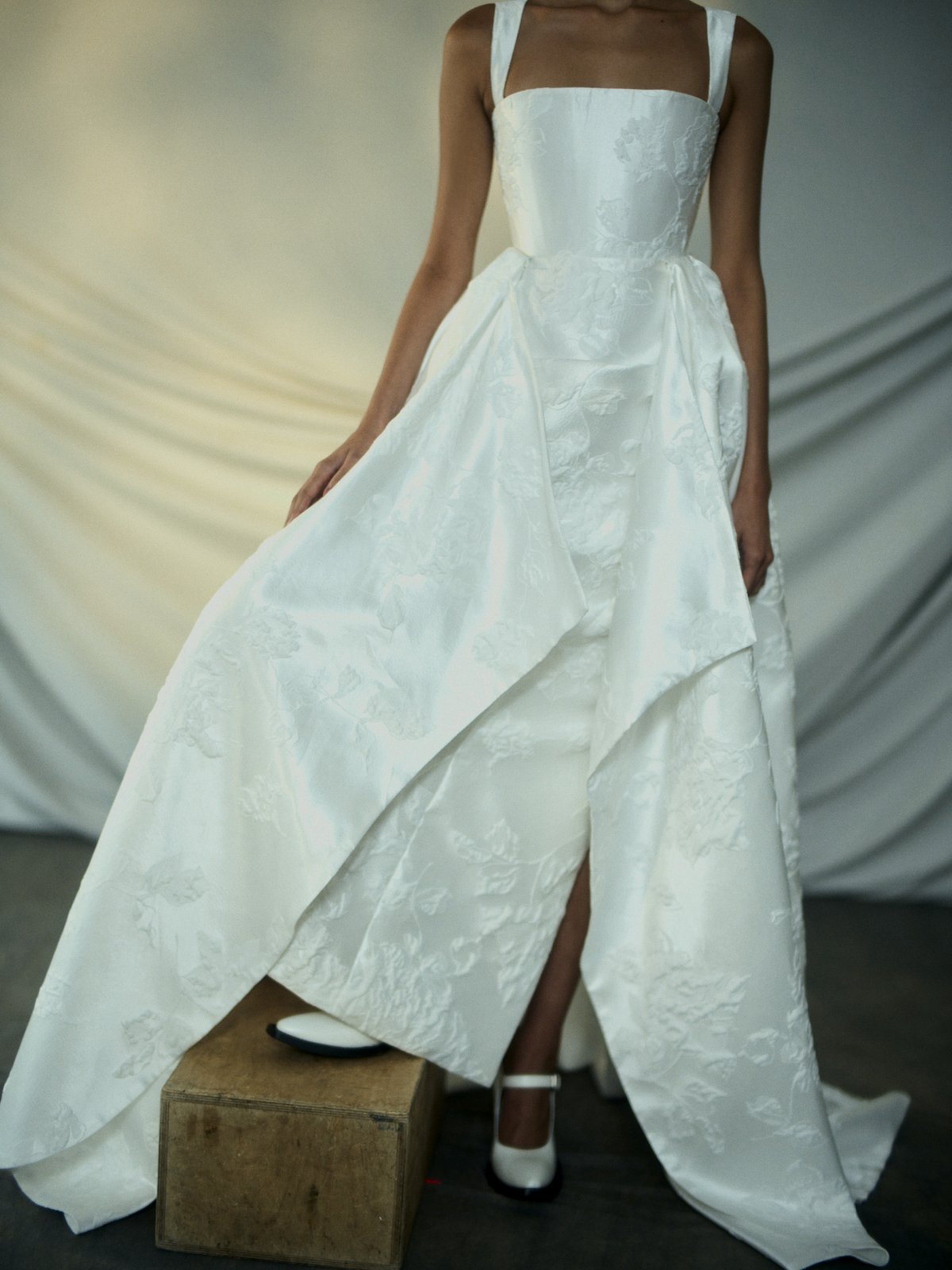 White wedding dress with a high-low hemline on a neutral background