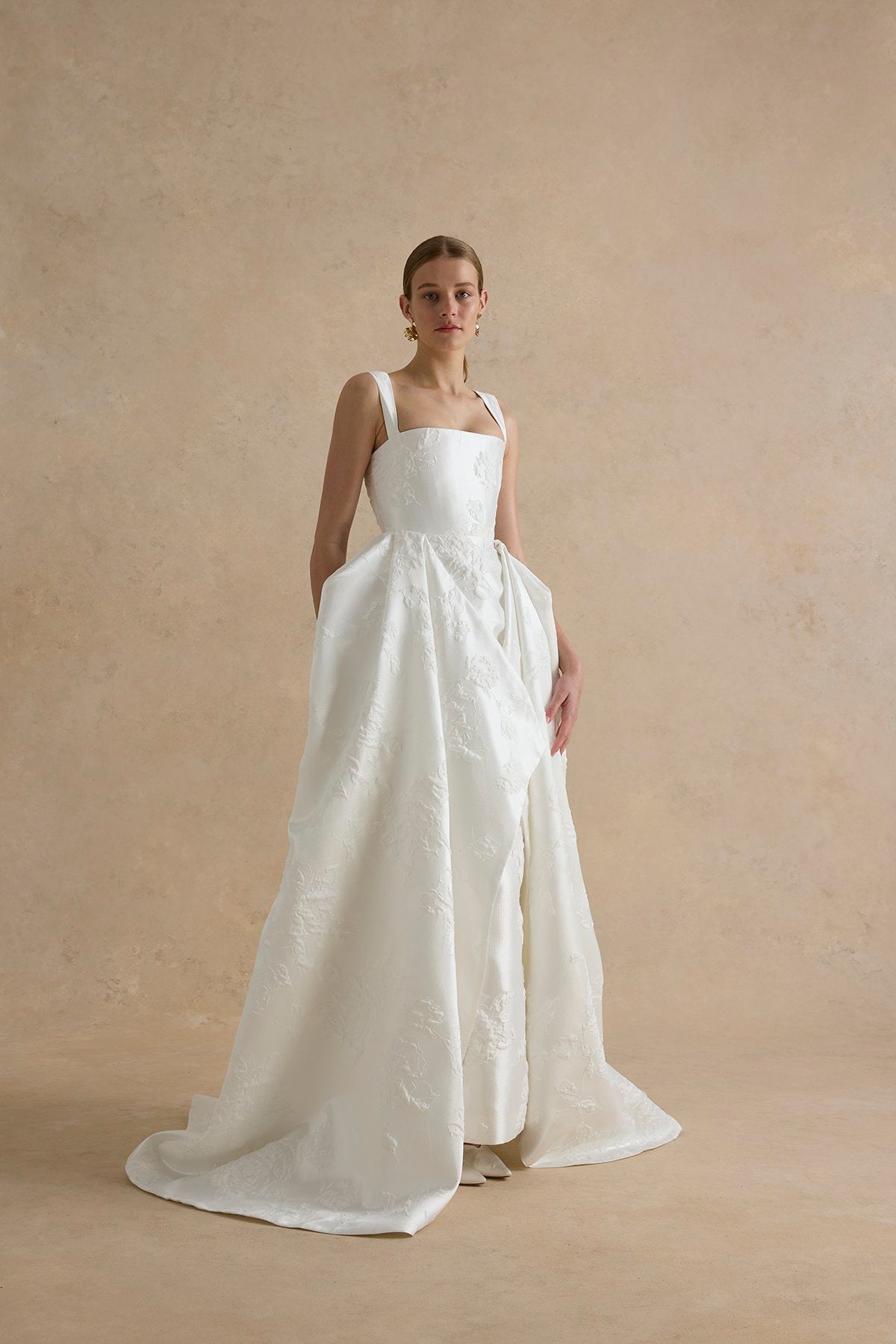Woman wearing a white wedding dress against a beige background