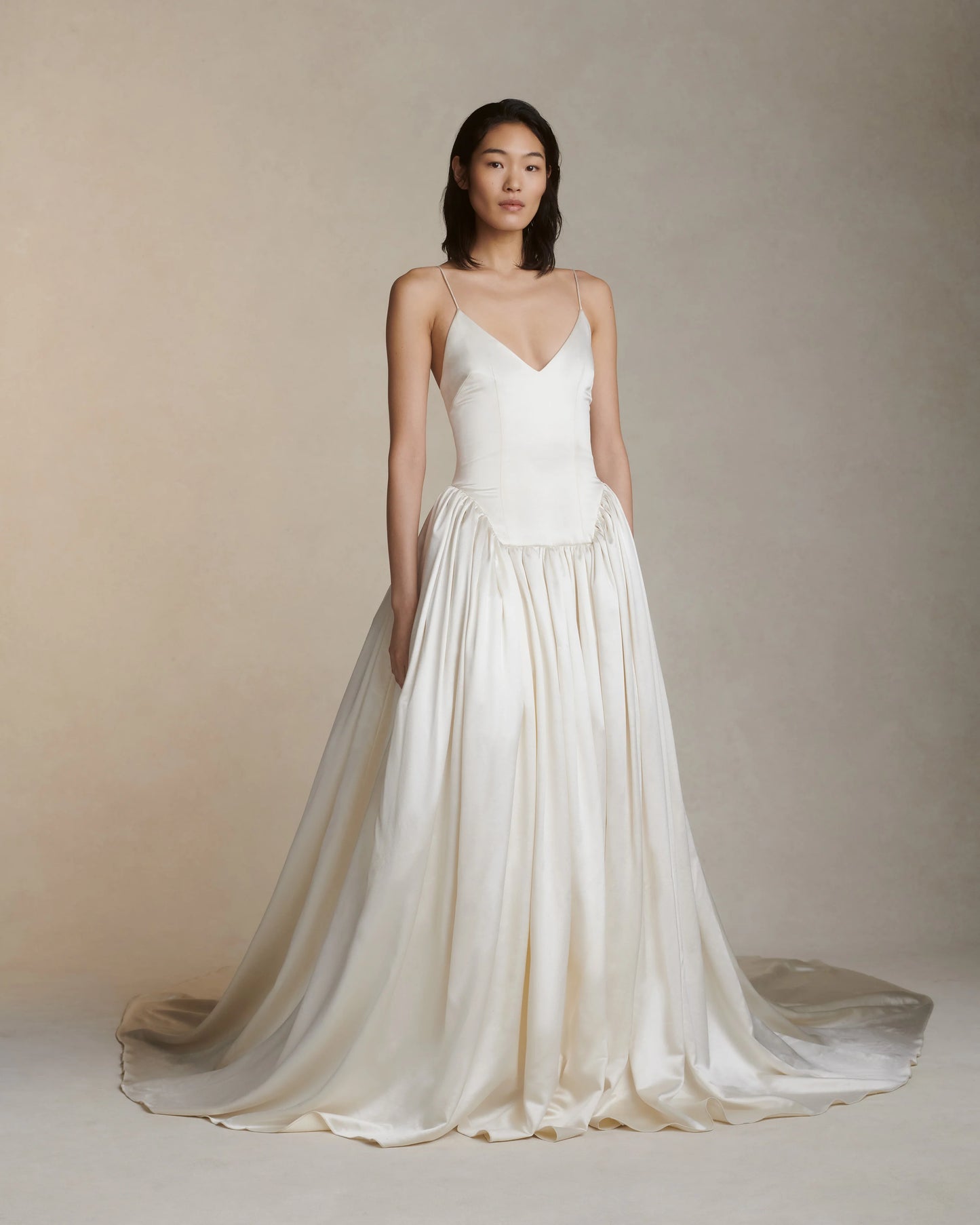 Woman wearing a white wedding dress against a plain background