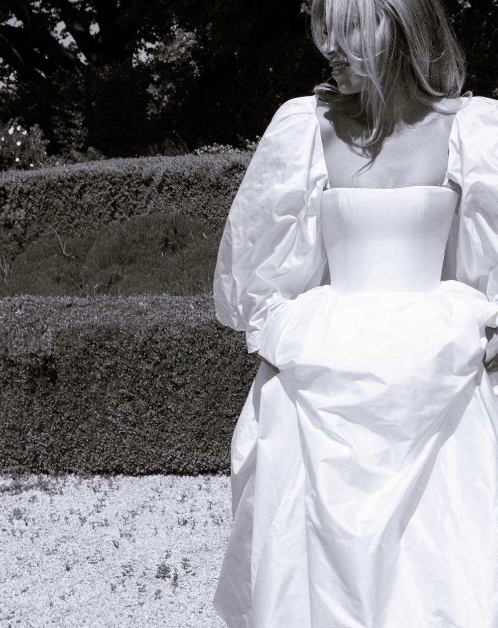 Person wearing a white dress with puffed sleeves in an outdoor setting.