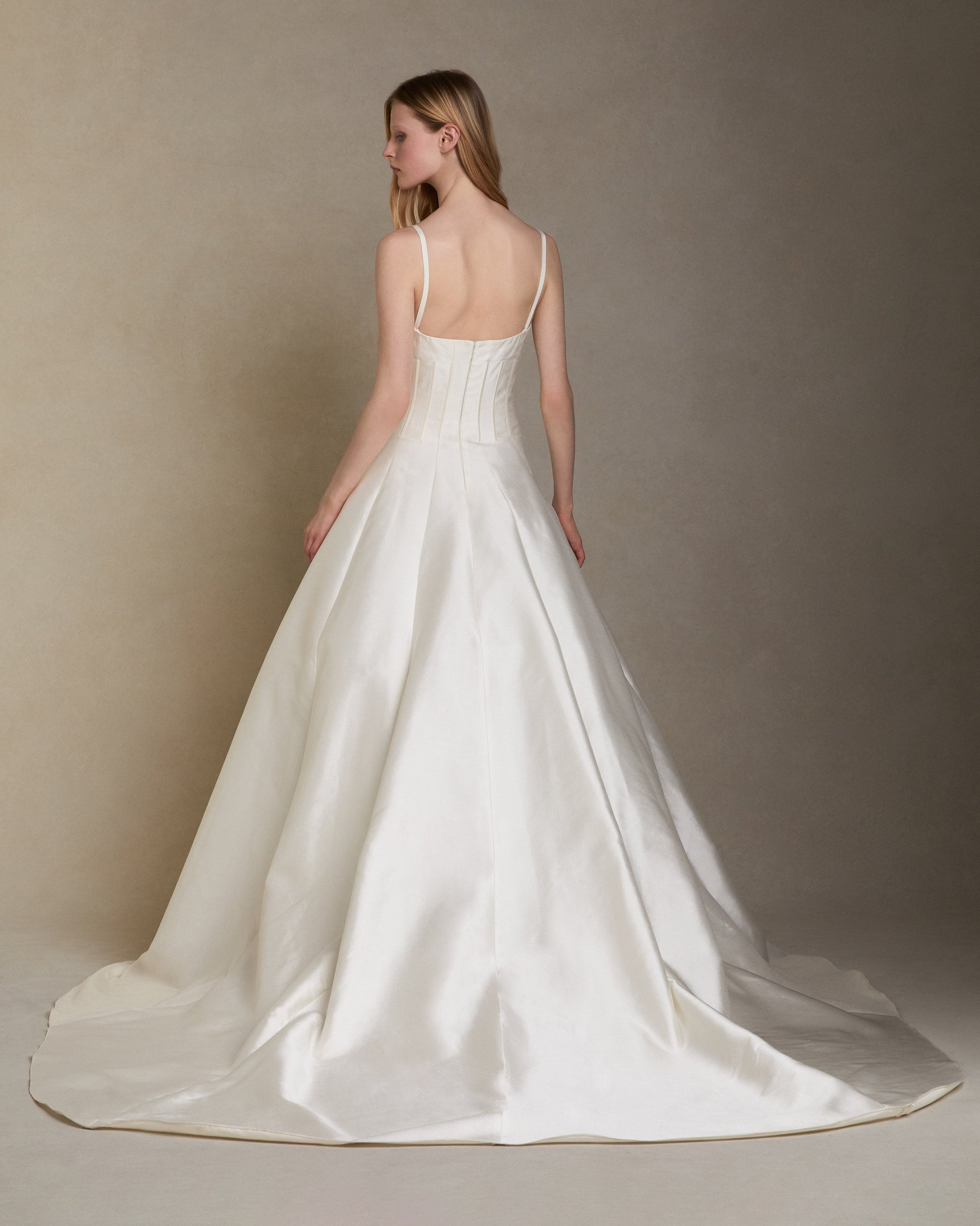 White wedding dress with a long train on a neutral background
