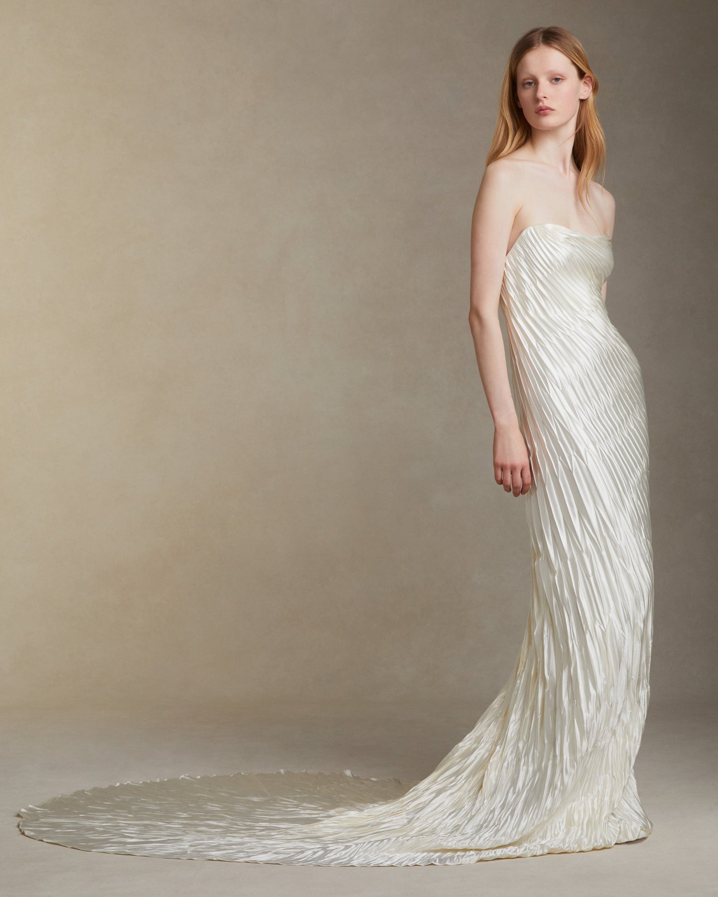 Woman wearing a long, elegant white dress against a neutral background