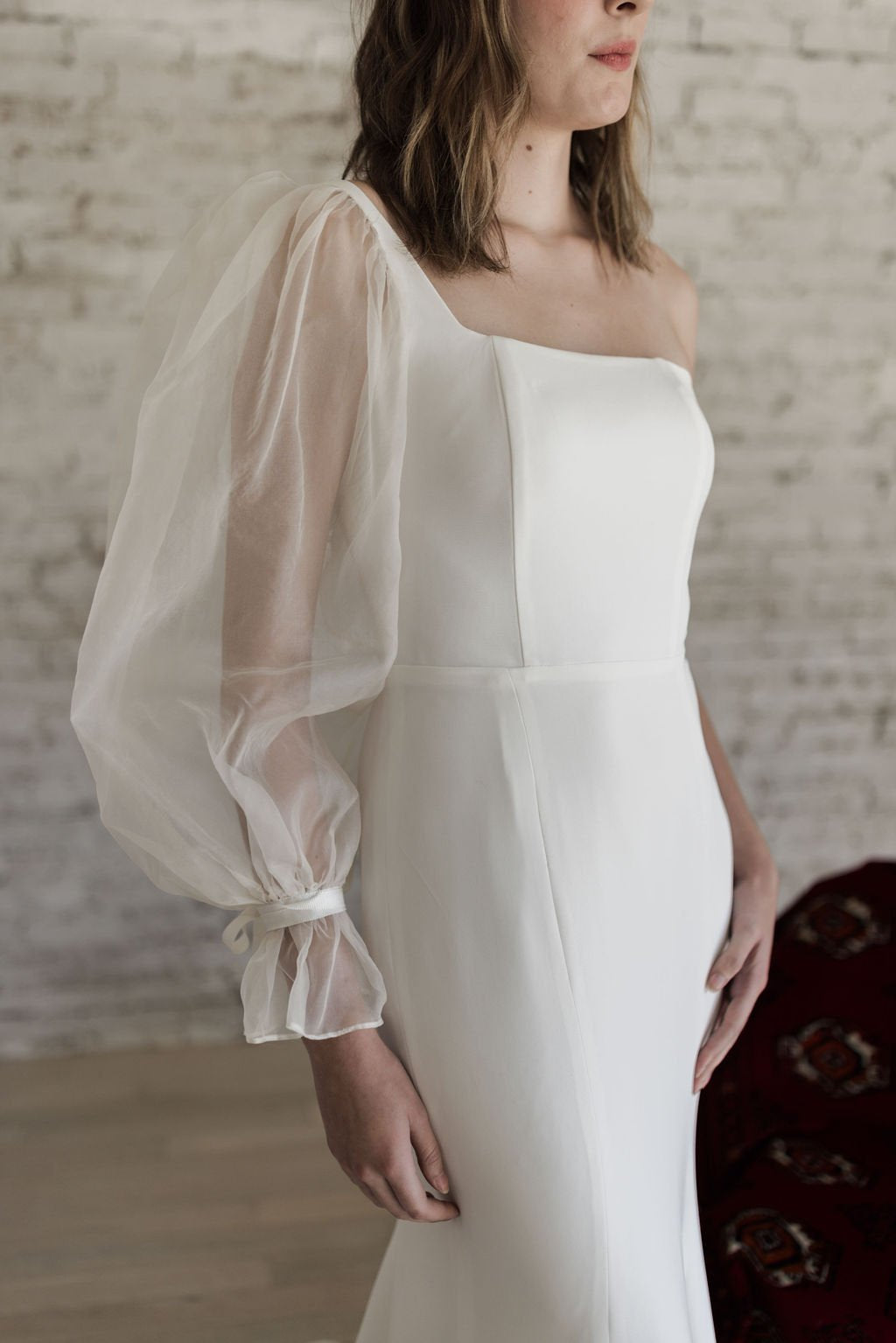 White wedding dress with sheer sleeves against a neutral background