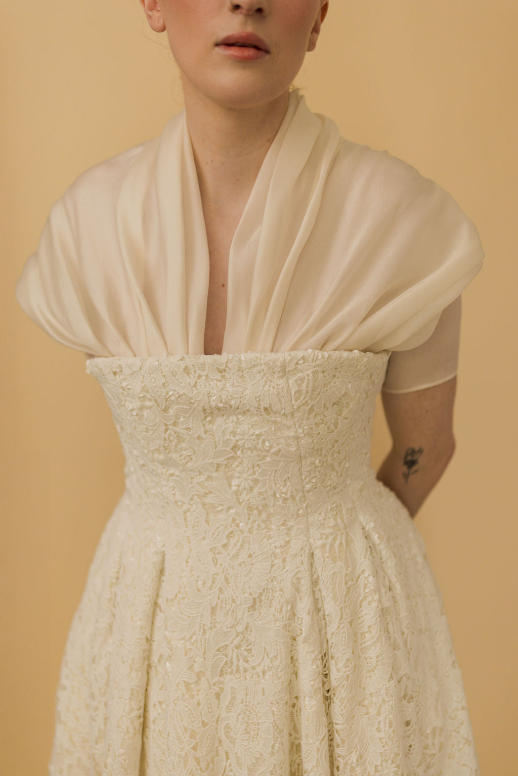 Woman wearing a beige lace dress against a beige background