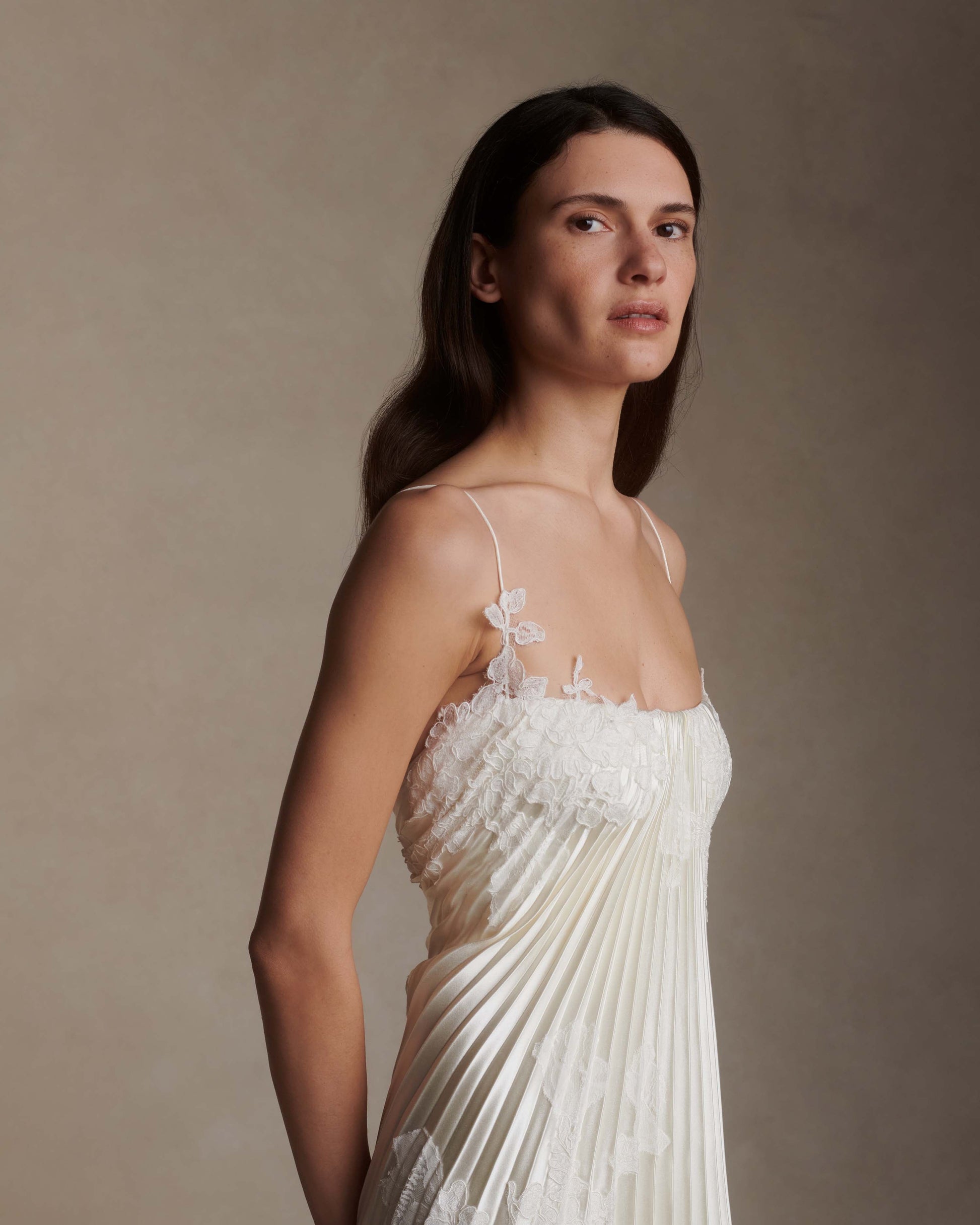 Woman wearing a white lace dress against a plain background