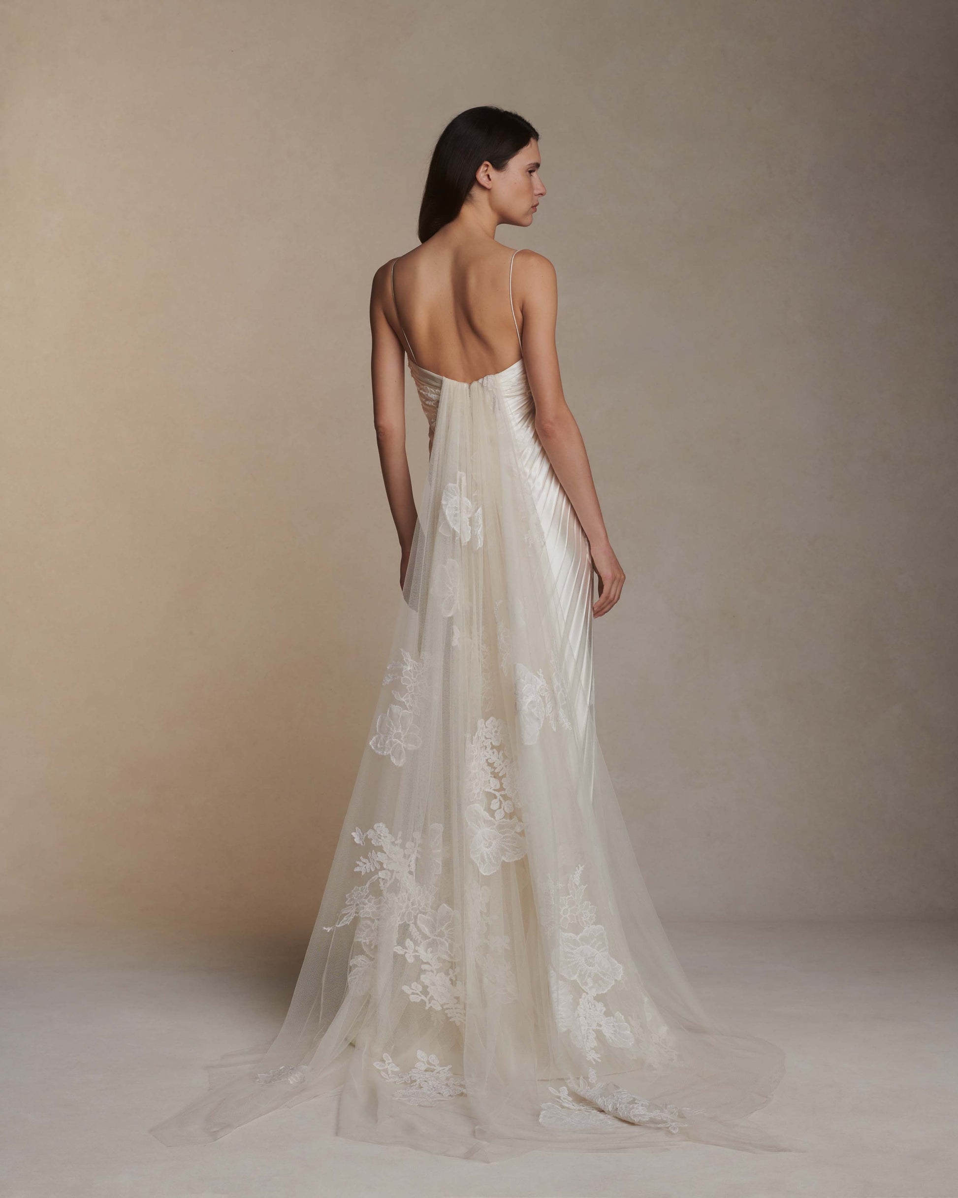 Woman wearing a white lace wedding dress with a plain background