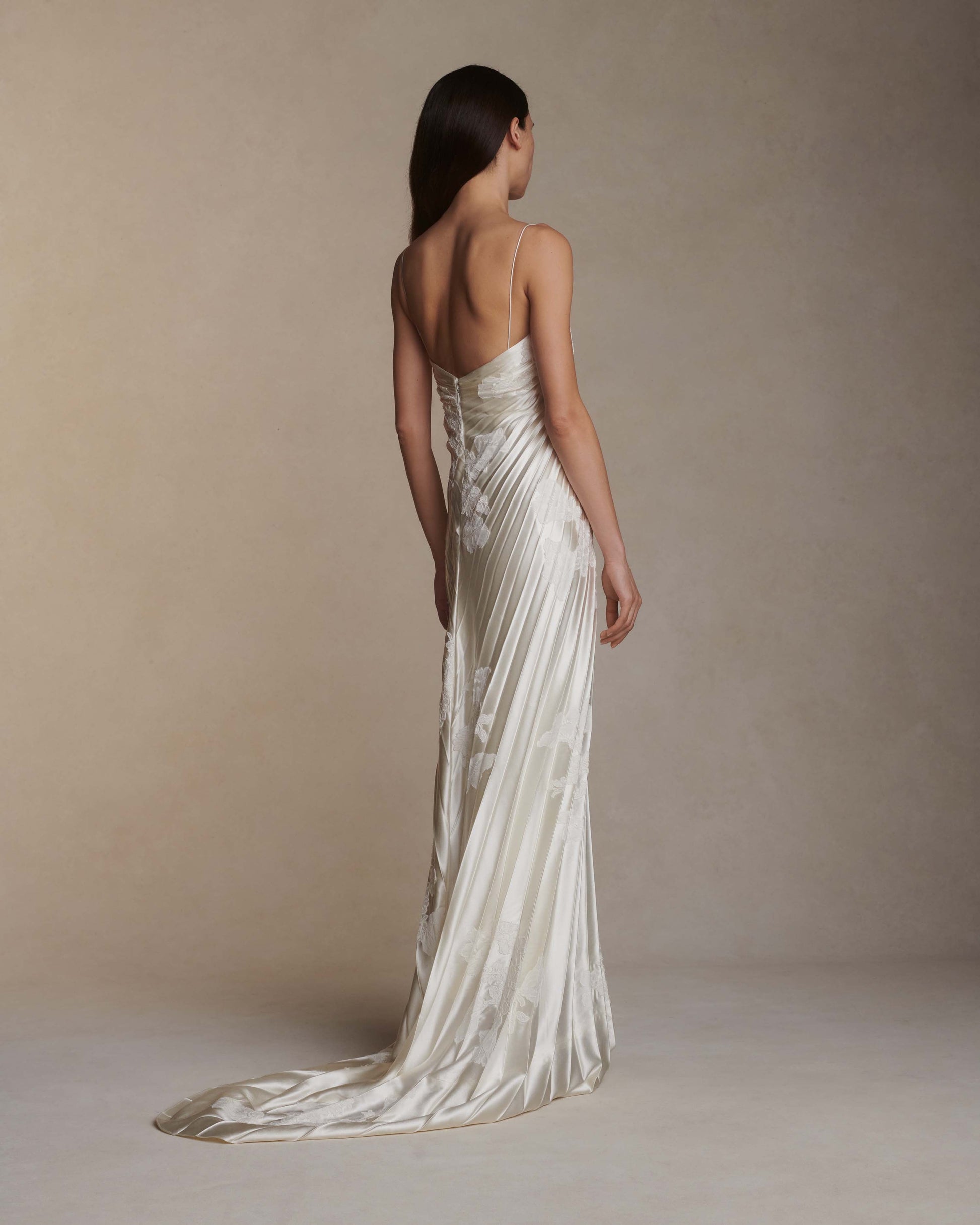 Woman wearing a white strapless gown with a long train against a beige background