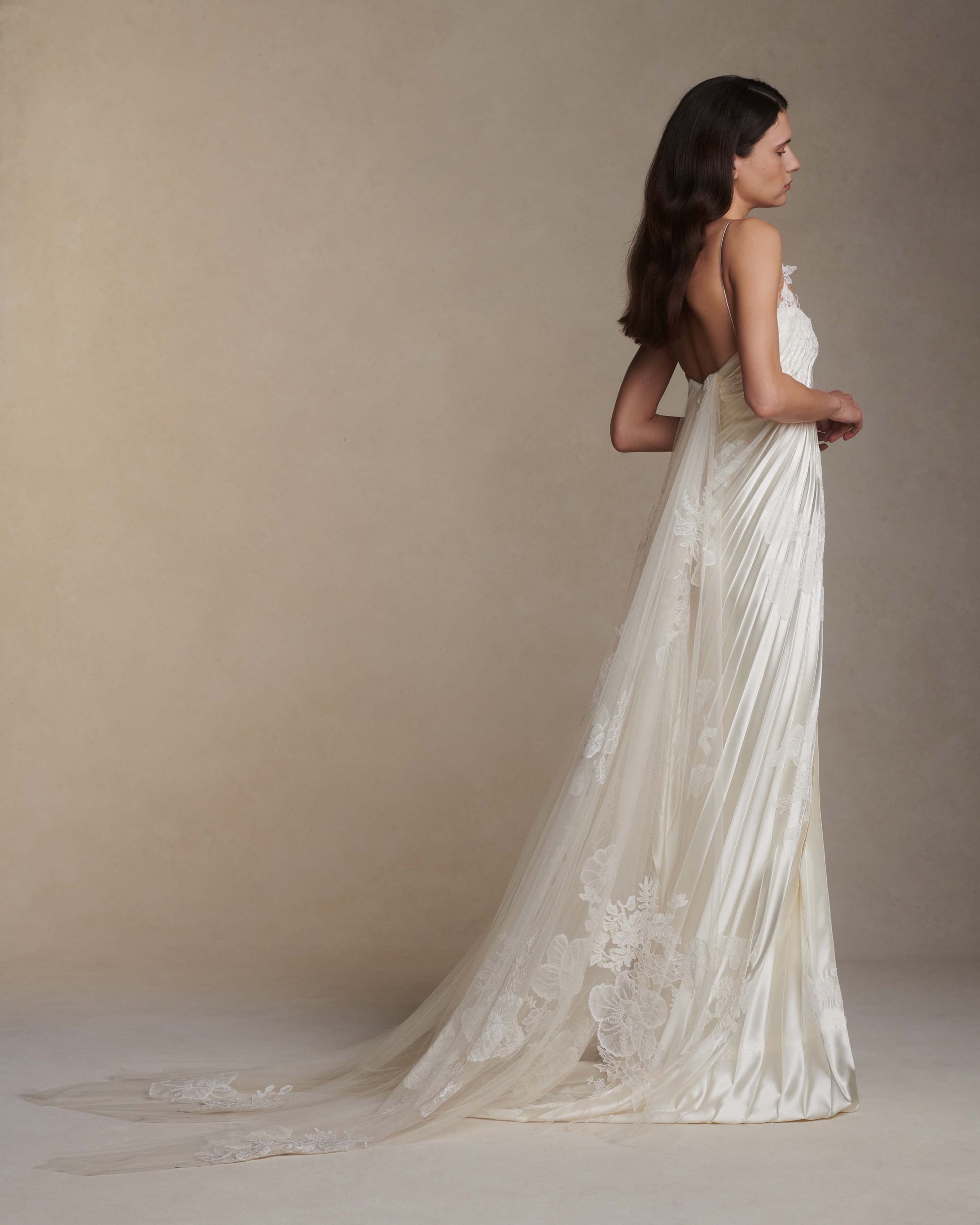 Woman wearing a flowing white lace dress against a beige background