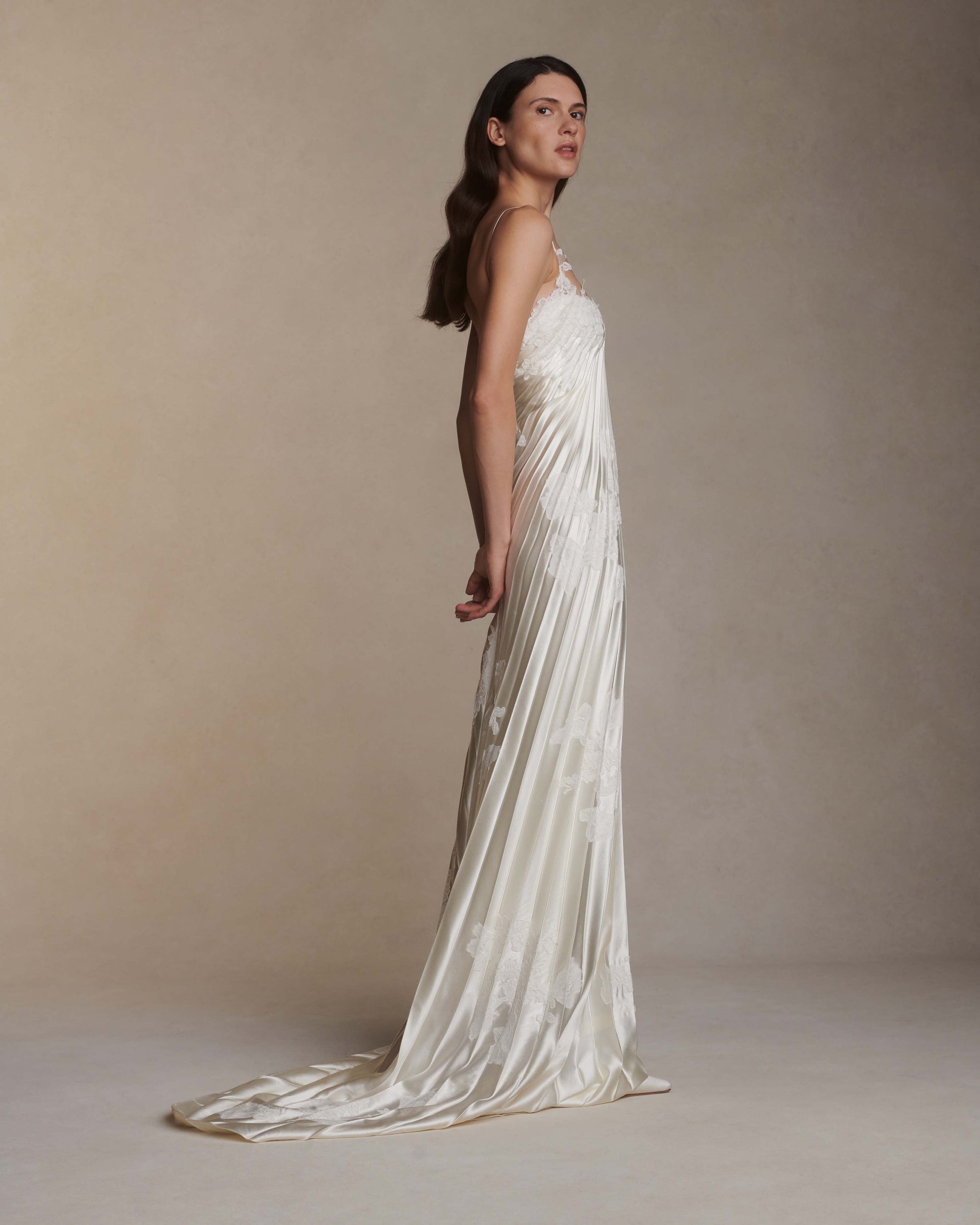 Woman wearing a long, flowing white dress against a neutral background