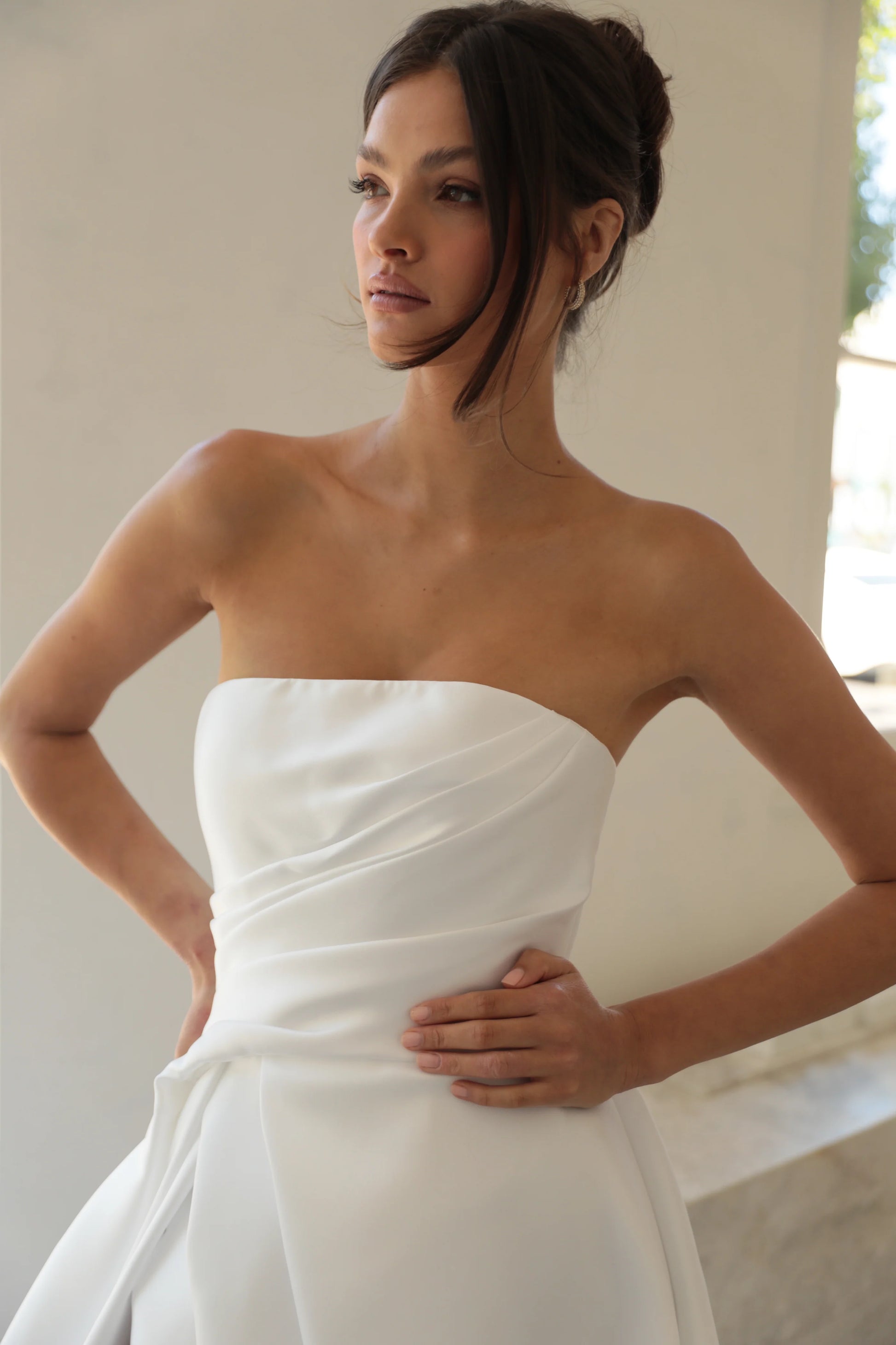 Woman wearing a strapless white wedding dress indoors.
