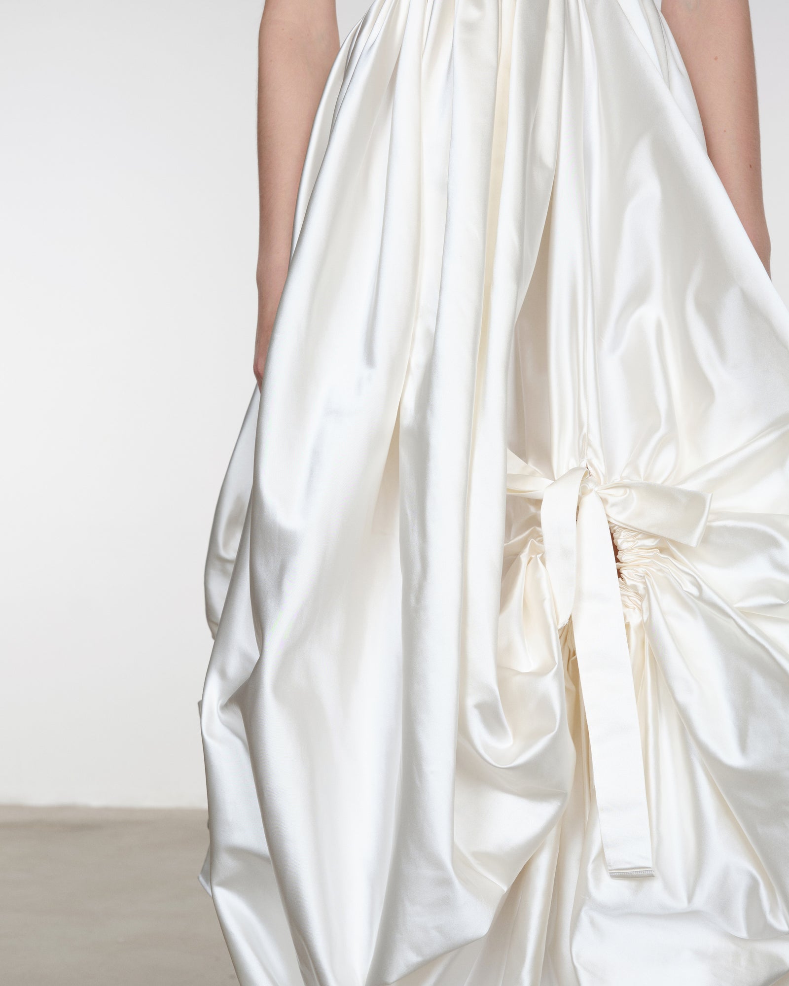 White satin fabric with a bow detail on a plain background