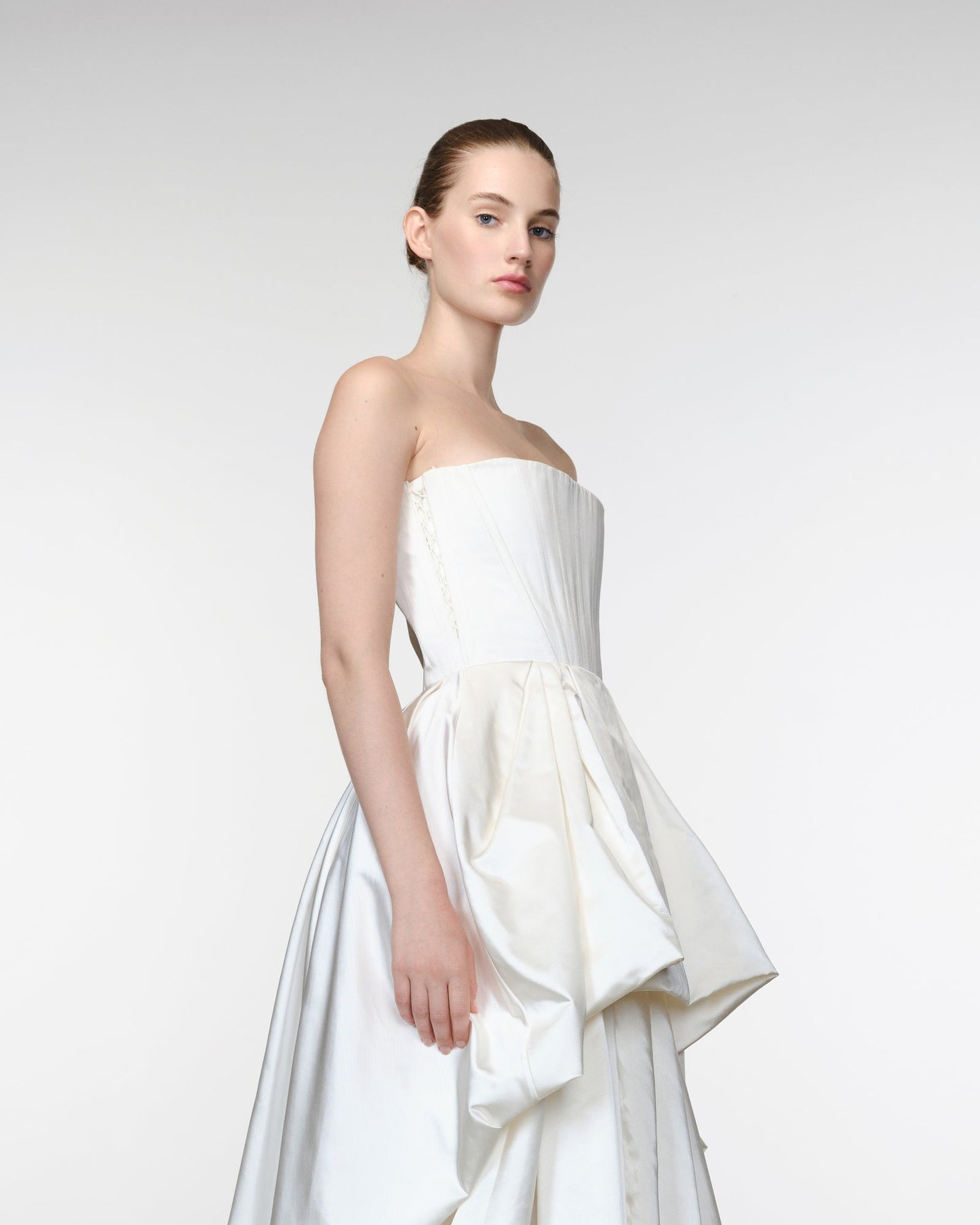 Woman wearing a white strapless dress against a plain background