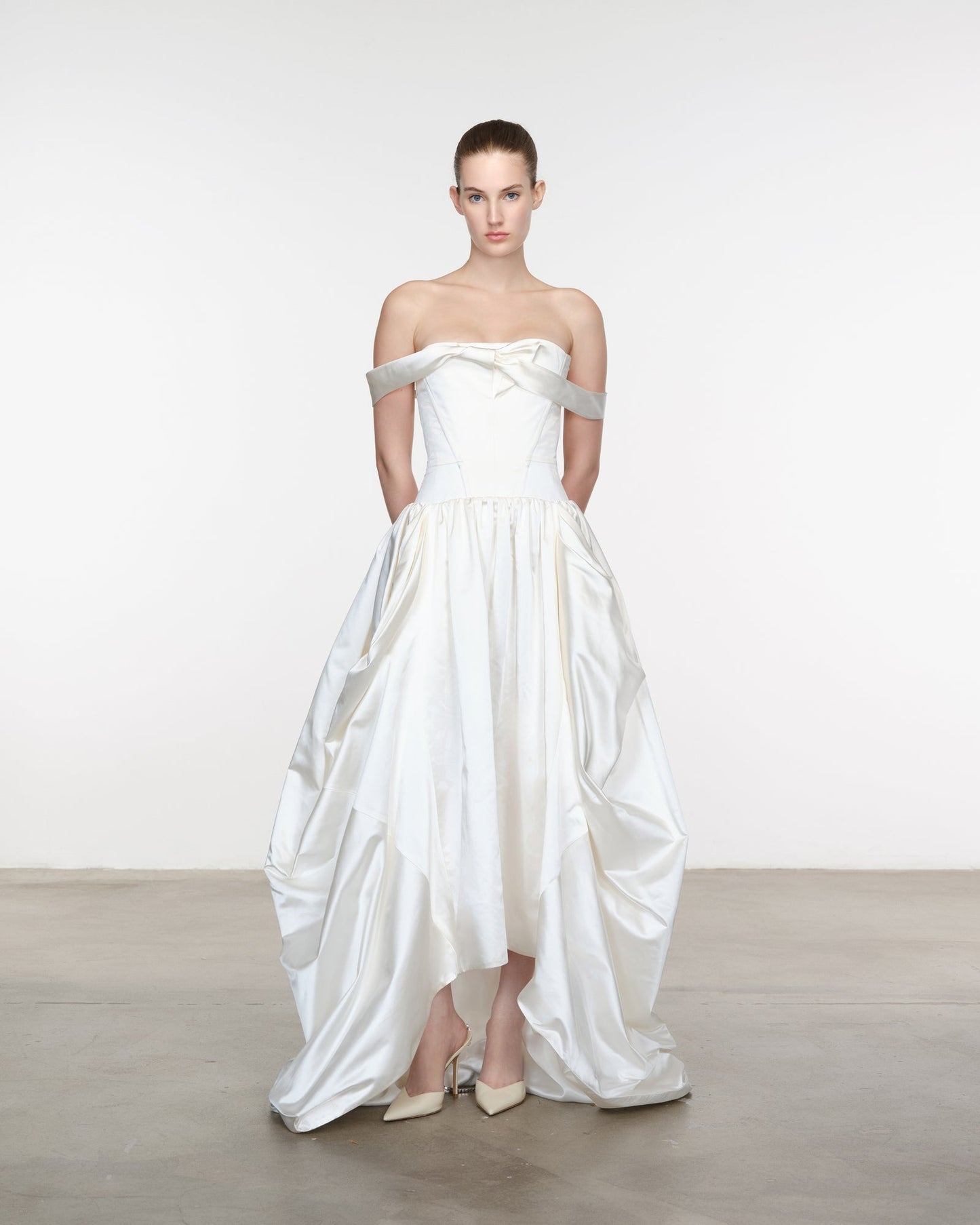 Model wearing a white strapless gown with silver straps against a plain background