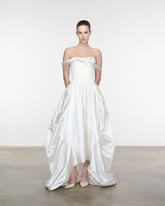 Model wearing a white strapless gown with silver straps against a plain background