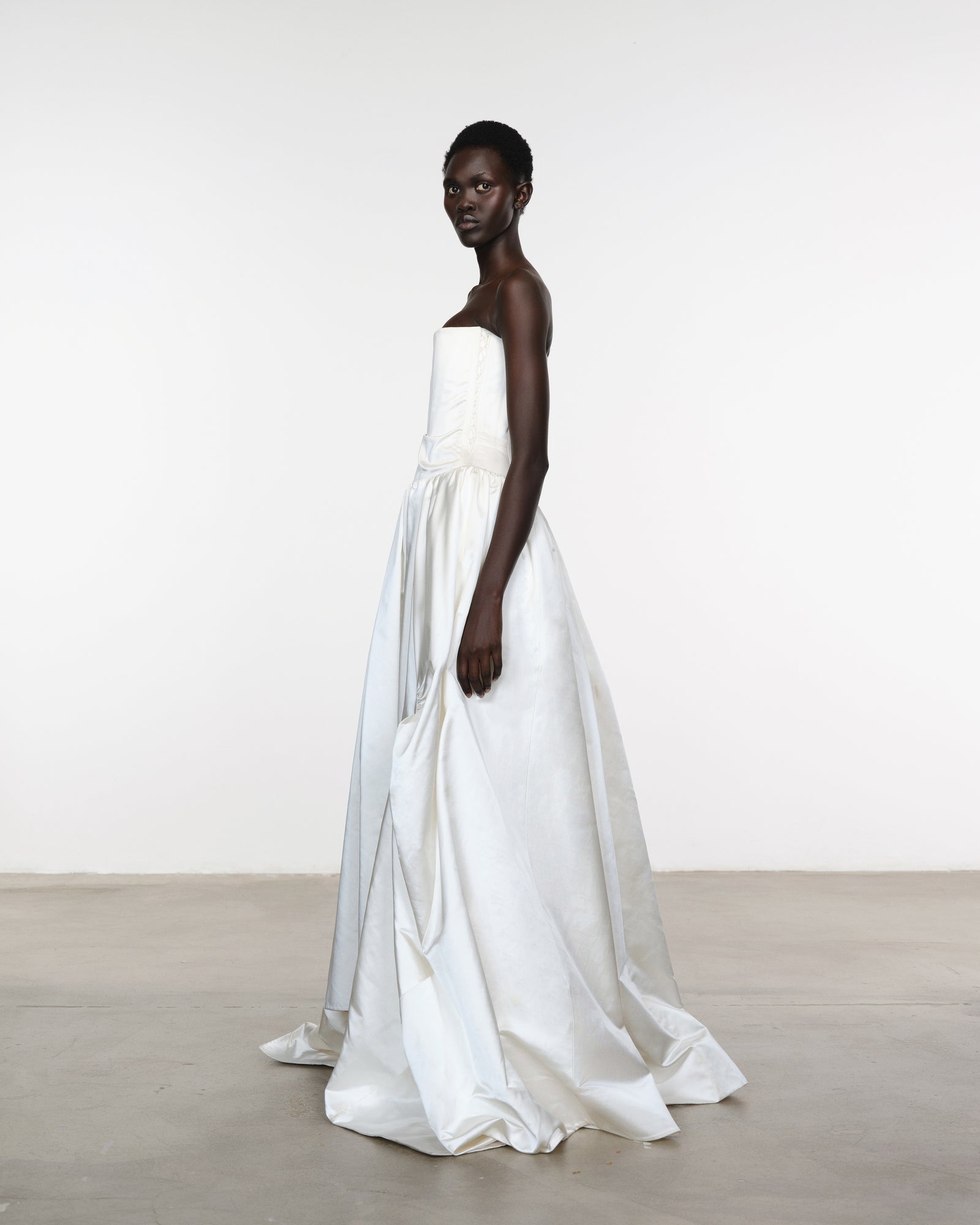 Model wearing a white dress with a plain background